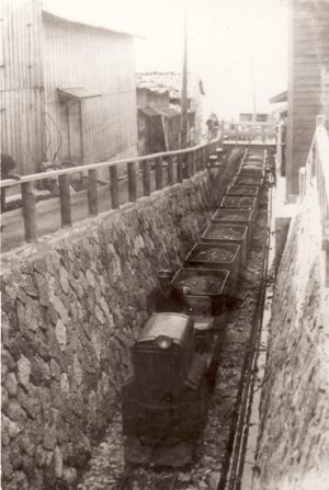 相川海岸沿いガソリン鉱車による浜石の運搬（昭和初期）（株式会社ゴールデン佐渡所蔵）​の画像