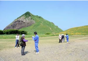 巨岩「大野亀」周辺で観光客をガイドする中学生
